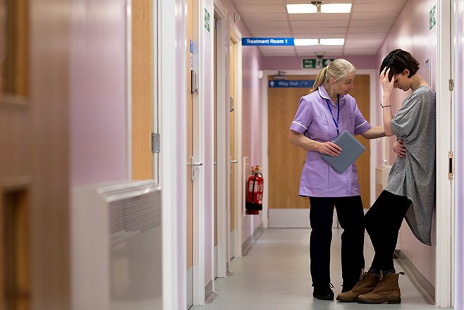 Nurse speaking to female patient in corridor