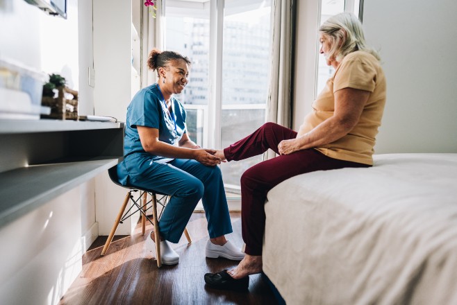 Nurse looking at older ladys lower leg Nurse looking at older ladys lower leg